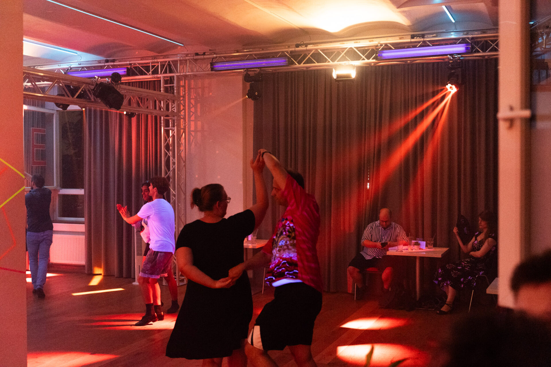 Paartanz tanzende Erwachsene in einem Tanzsaal, der von roten Lichtstrahlen beleuchtet wird